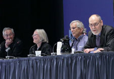 Panel of leaders from across NIH sit at long conference table on stage, some speak into microphones, look pleasant, engaged