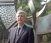 NIH Director Dr Francis S Collins stands in front of large genomics-inspired status in India 