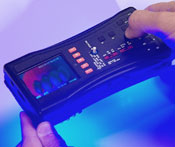 Close up of hands holding FDA Counterfeit Detection Device-3 CD-3, black electronic box with many buttons emits glow on bottom