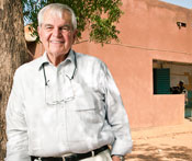 Dr Marc LaForce leans against a tree in the shade in front of a health clinic in Africa