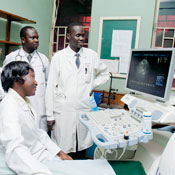 Medical workers in white coats observe large monitor