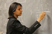 Dr Shweta Bansal intently works a complex math problem with chalk on a blackboard