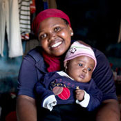 Young woman smiling at camera holds young baby