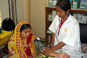 Female medical worker takes blood pressure of woman seated in a clinic