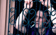 Man smoking stands in doorway behind a metal fence