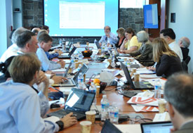Many people seated at a large conference table discuss and collaborate at the Center for Global Health Studies