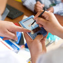 Close up of data entry on mobile device with a stylus, multiple people point to screen