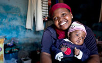 Young woman smiling at camera holds young baby