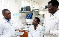 Photo by Richard Lord/Fogarty NIH, three male researchers in white coats consult, work together in lab in Uganda