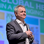 Dr. Jeremy Farrar smiles while standing on stage after presenting the Barmes Global Health Lecture.