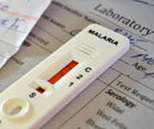 close up of white malaria test showing red indicator sitting on top of sheet of paper with title laboratory