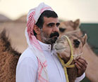 Man stands and strokes camel's neck