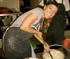 Dr. Elizabeth Vaughan, smiling, stirs large metal pot full of white porridge with large wooden spoon