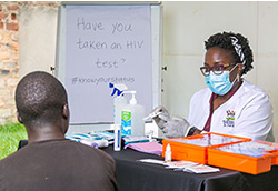 Dr. Patience A. Muwanguzi pointing to test results meets with a patient in a clinic