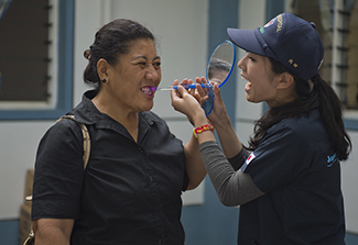 a technician from the Japan Self-Defense Forces Dental Corps, shows a Tongan citizen how to brush teeth more efficiently at a he
