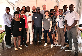 Acting Fogarty Director Peter Kilmarx and members of the second APTI cohort pose for a photo inside a white tent.