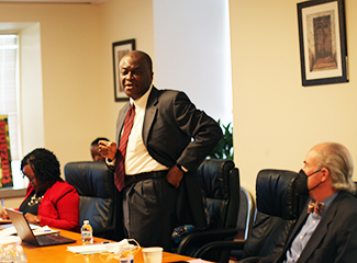 Dr. George Mensah (standing) speaks as Dr. Peter Kilmarx (right) and others listen in. 