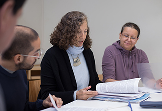 In this photo Dr. Florencia Luna (center) is seated at a table talking with trainees.