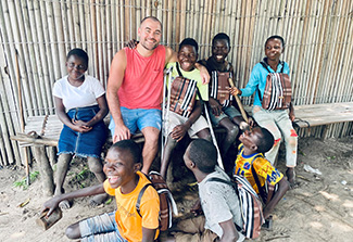 In this photo shot in Kahemba, Dr. Matthew Bramble is pictured wearing a t-shirt and surrounded by a group of children who have been affected by konzo, a paralyzing disease