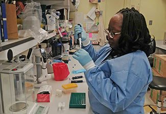Dr. Ajakaye Oluwaremilekun Grace wearing blue scrubs works in a lab at the NIH Clinical Center in Bethesda, Maryland during her 