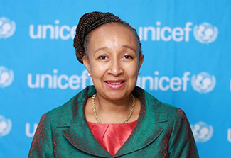 Photo of Dr. Joan Matji with a UNICEF banner behind her