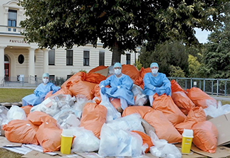 In this photo, two health care professionals, recognizable due to their scrubs, sit on a stack of garbage bags