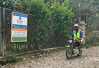 Photo of MotoMeds driver on a motorcycle next to the MotoMeds call center in Gressier, Haiti. 