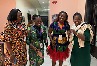 The photo on this page shows four women laughing together in an office hallway. They are research administrators who have taken part in the training sessions sponsored by UNN and UCSD. All wear colorful African dresses.