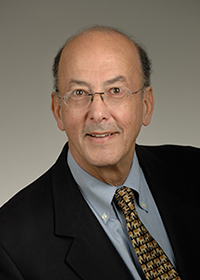 The photograph shows a headshot of Dr. Roger I. Glass, wearing a black suit, blue shirt, patterned tie and glasses.