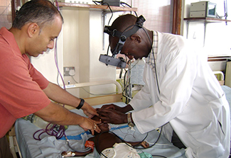 In this photo, Dr. Chandy John and a student doctor work on an infant patient in a Uganda hospital.