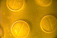 Close up of four pills in pack scanned using FDA tool, yellow glow, authentic pills show regular, even coloring, no spots