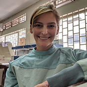 The photo shows Ashley Karczewski, DDS, smiling with lab equipment behind her