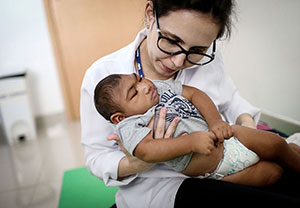 In Brazil, a doctor performs physical therapy on an infant born with microcephaly