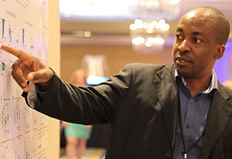 Dr. Emmanuel Balandya points to an item on a scientific poster in a conference room