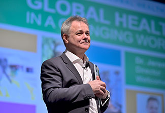 Dr. Jeremy Farrar smiles while standing on stage after presenting the Barmes Global Health Lecture.