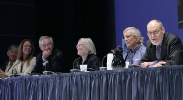 Panel of six leaders from across NIH sit at long conference table on stage, some speak into microphones, look pleasant, engaged