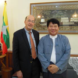Fogarty Director Dr Roger I Glass stands with Burma's health minister Dr Pe Thet Khin, Burmese flag in background