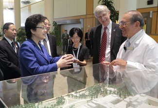 Chinese delegation gathers around architectural model in lobby of clinical center with Dr Francis Collins and Dr John Gallin