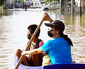 A woman and a child in a boat on a flooded street.