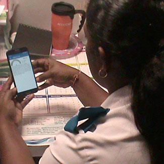 Health worker uses app on a mobile phone, view from over her shoulder