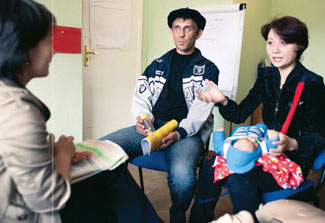 Male and female, who holds infant in lap, meet with clinician in an office