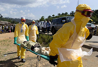 Workers wearing personal protective equipment carry a person on a stretcher