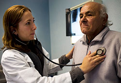 Medical worker examines elderly male patient.