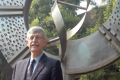 NIH Director Dr Francis S Collins stands in front of large genomics-inspired status in India