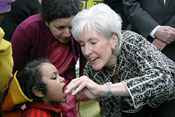 Kathleen Sebelius administers polio vaccine to young child, woman looks on closely from behind