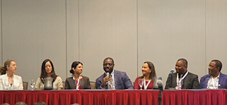 Alumni sit at a table on the stage during a session at the CUGH 2023 conference