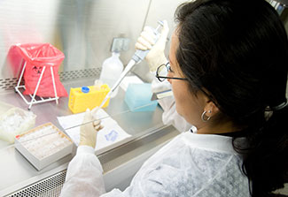 Female researcher prepares samples under a hood in a lab at UPCH in Peru.