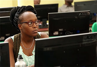 Female student working at a computer in a classroom.