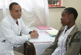 Photo: Dr. Gerald Bloomfield speaks to young male patient, both seated, a table covered with papers between them