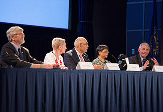 Panel of 5 researchers seated at table in auditorium